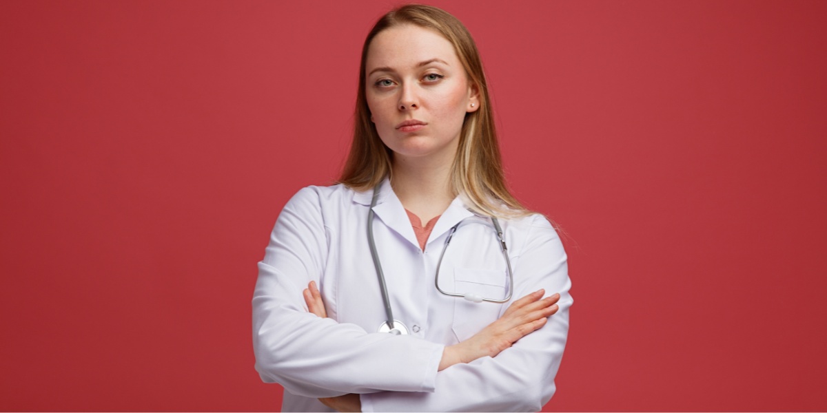 Blonde female doctor with arms folded while looking at camera