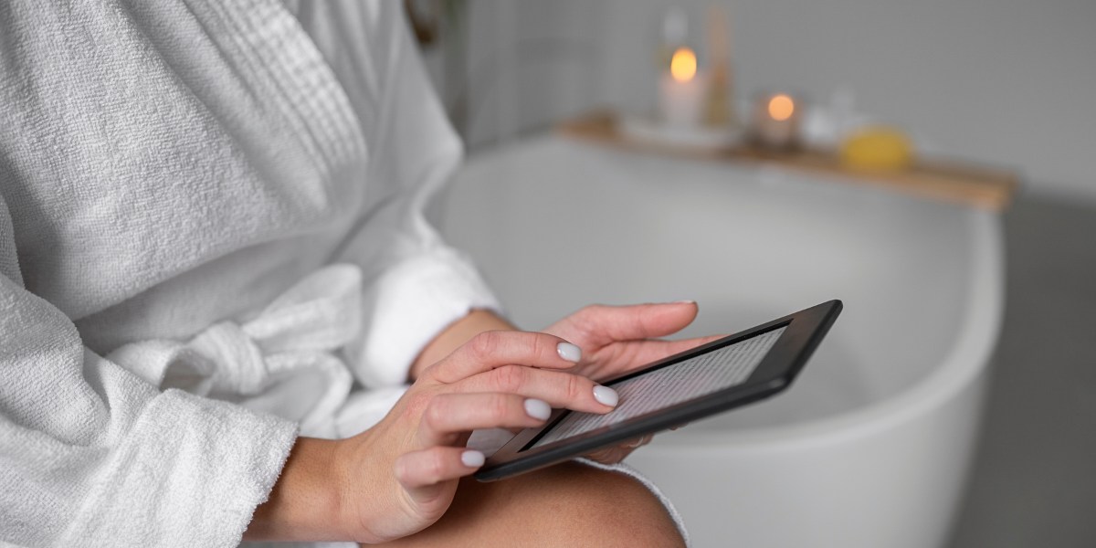 Half angle view of a young woman using tablet while sitting on bathtub