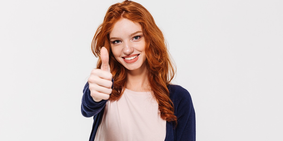 Young cheerful red-haired girl showing thumbs up - Where to find licensed adult videos