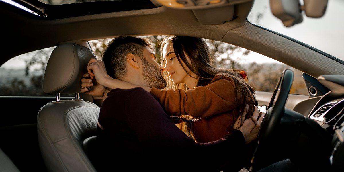 Side close-up of a couple in a romantic pose in a car - car sex