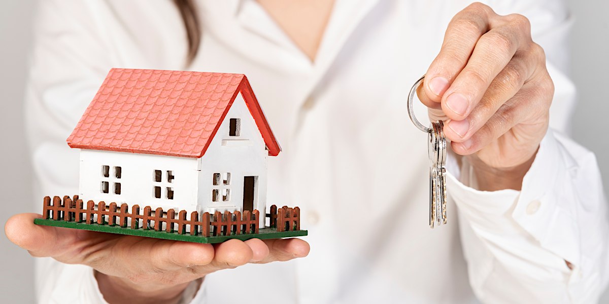 A woman holding a model house in her right hand and a set of keys in her left hand - New life of Gemma Massey